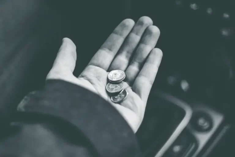 Wyciągnięta dłoń z monetami symbolizująca wsparcie finansowe i pomoc.