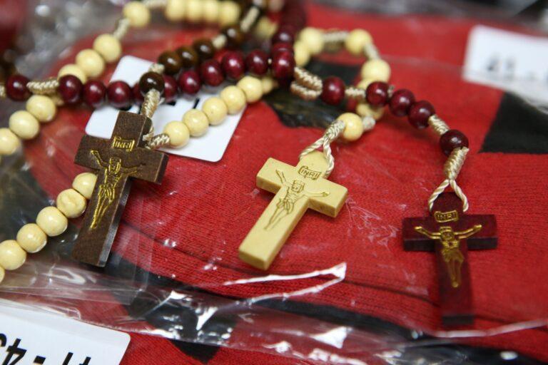 Drewniane krzyże od różańców ułożone na zapakowanym swetrze w różnych kolorach jako przygotowana darowizna.