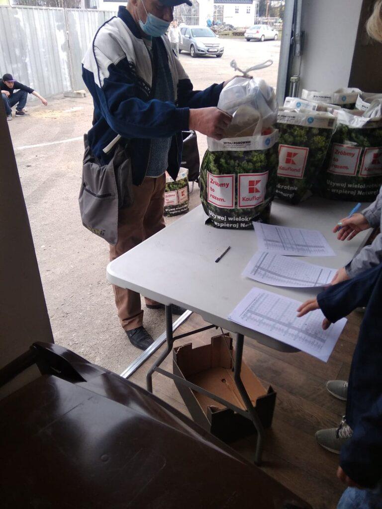 Mężczyzna z torbami zawierającymi produkty spożywcze przekazane w ramach pomocy.