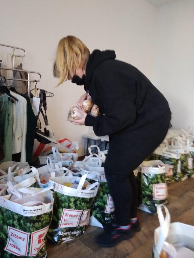 Kobieta pakująca produkty spożywcze do toreb w ramach akcji pomocowej dla osób potrzebujących.