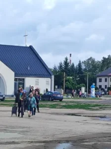 Osoby zmierzają w stronę punktu pomocy, gdzie mogą odebrać paczki z darami żywnościowymi