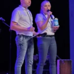 Dwóch członków fundacji na scenie z puszkami, przedstawiających cel zbiórki.