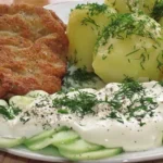 Talerz z kotletem schabowym, ziemniakami i mizerią.