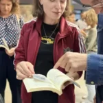 Uczestnicy warsztatów oglądają książkę podczas wydarzenia.