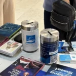 Książki rozłożone na stoliku podczas zbiórki charytatywnej oraz puszki na datki.