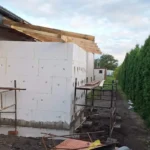 Dobudowa pomieszczenia z ociepleniem elewacji styropianem i drewnianą konstrukcją dachu.