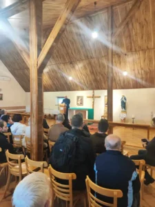 Grupa pielgrzymów podczas konferencji prowadzonej przez księdza.